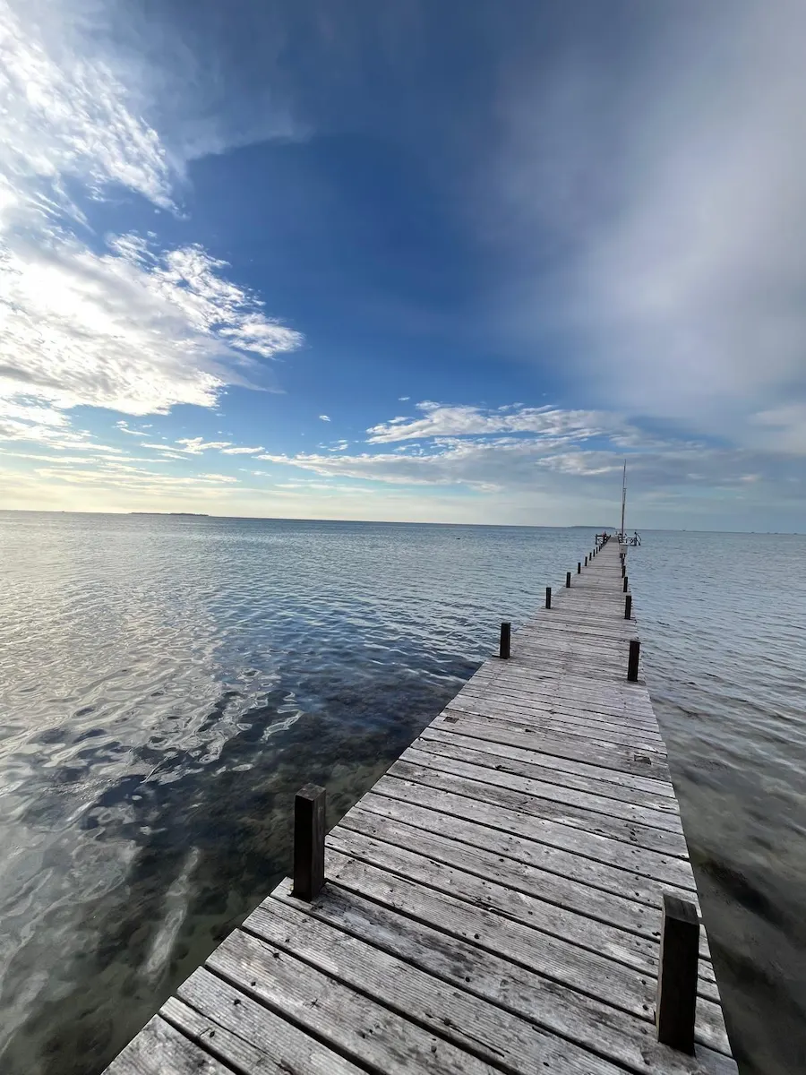 Pier over rustig water bij bewolkte hemel